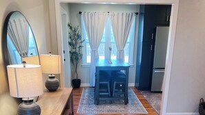 A room with a wooden floor, a wooden console table with a lamp, a mirror, and a view of a dining area with a table and chairs through a doorway. - Cozy 2-bedroom house in Enid (Enid)