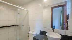 A modern bathroom with a glass shower enclosure, a toilet, a sink, and a mirror. - House in Condo w/ Pool and Barbecue Grill Bme0001 (Porto Seguro)