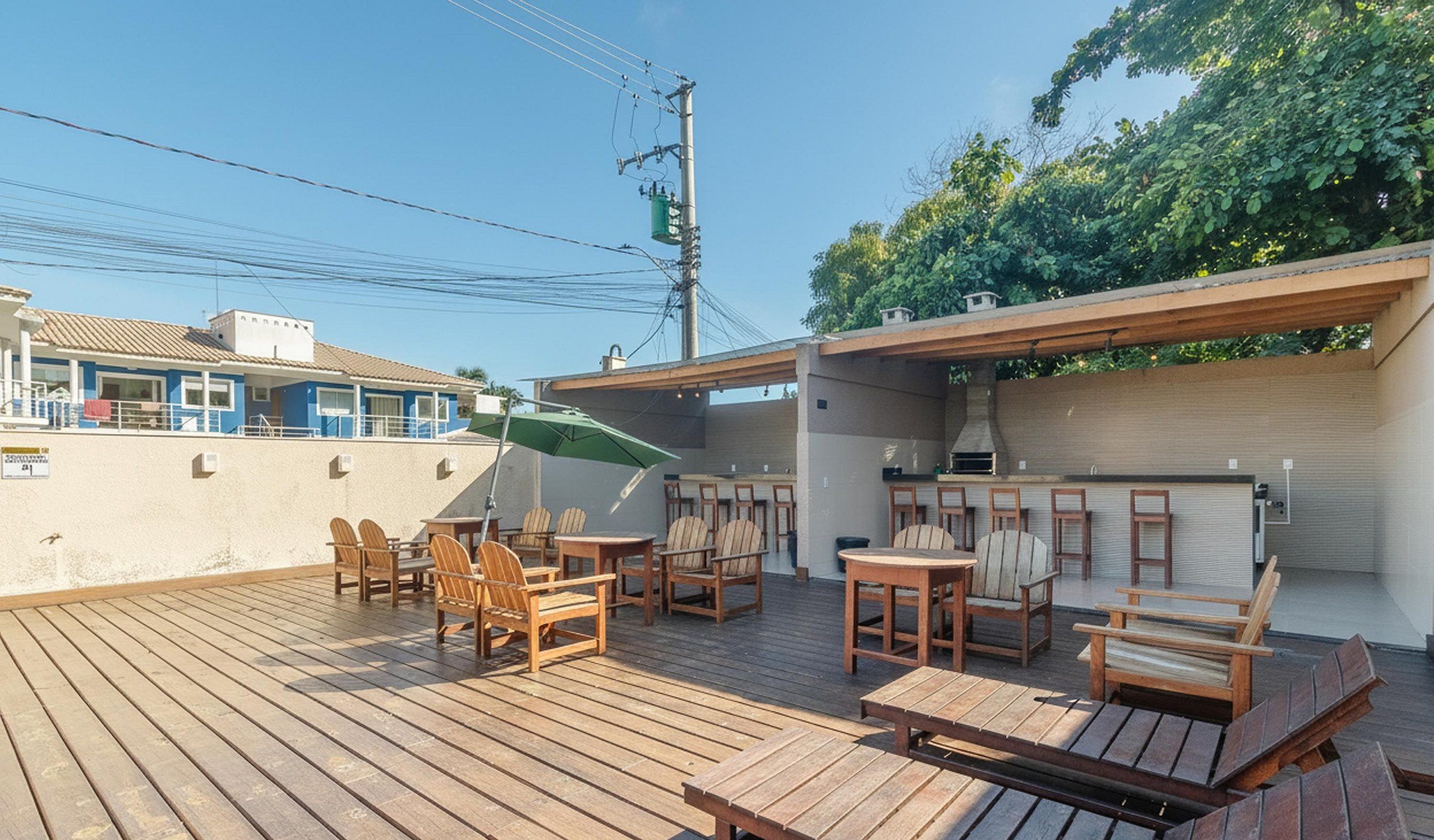 A wooden deck with outdoor seating, a barbecue area, and a view of a building with a blue facade.