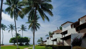Ein Resort mit weißen Gebäuden, Palmen und einem Weg zum Strand.