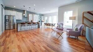 Una cocina amplia con electrodomésticos modernos, un comedor con taburetes de bar y una sala de estar con sofás.