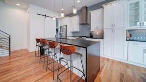 Una cocina moderna con armarios blancos, una isla central con taburetes altos e iluminación colgante.