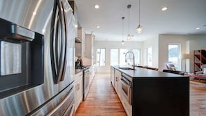 Una cocina moderna con electrodomésticos de acero inoxidable, suelo de madera e iluminación colgante.