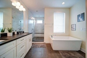 Un baño moderno con ducha a ras de suelo, una bañera grande y un tocador con espejo.