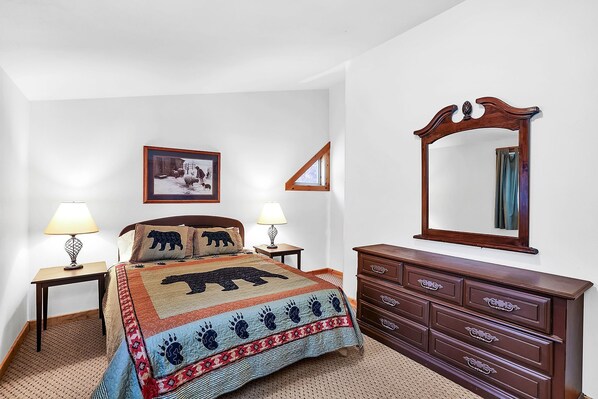 A bedroom with a bed, two bedside tables with lamps, a dresser, a mirror, and a framed picture on the wall. - Big Timber - Cabin in McCall, ID (McCall)