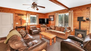 A cozy cabin interior with a wooden interior, leather sofas, a television, and a fireplace. - Big Timber - Cabin in McCall, ID (McCall)