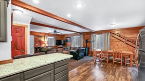 A spacious living area with a wooden floor, a kitchen with granite countertops, and a dining area with wooden chairs. - Big Timber - Cabin in McCall, ID (McCall)
