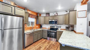 A modern kitchen with stainless steel appliances, wooden cabinets, and a granite countertop. - Big Timber - Cabin in McCall, ID (McCall)