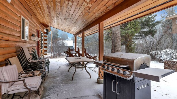 A covered patio with a wooden ceiling, a grill, and outdoor seating. - Big Timber - Cabin in McCall, ID (McCall)