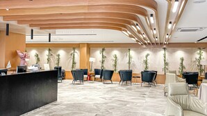 A modern reception area with a curved wooden ceiling, marble flooring, and several seating options including chairs and sofas. - FAFA Aqua Blue Hotel (Golem)