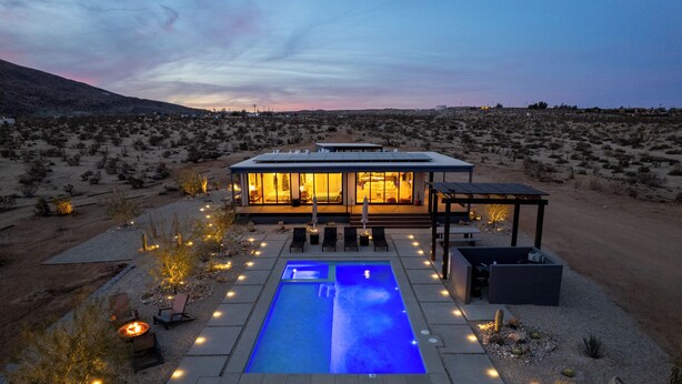 Una casa moderna con piscina, area relax esterna e paesaggio desertico.