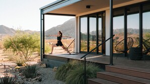 Una casa moderna con un patio, una persona che si allena e vista sul paesaggio desertico.