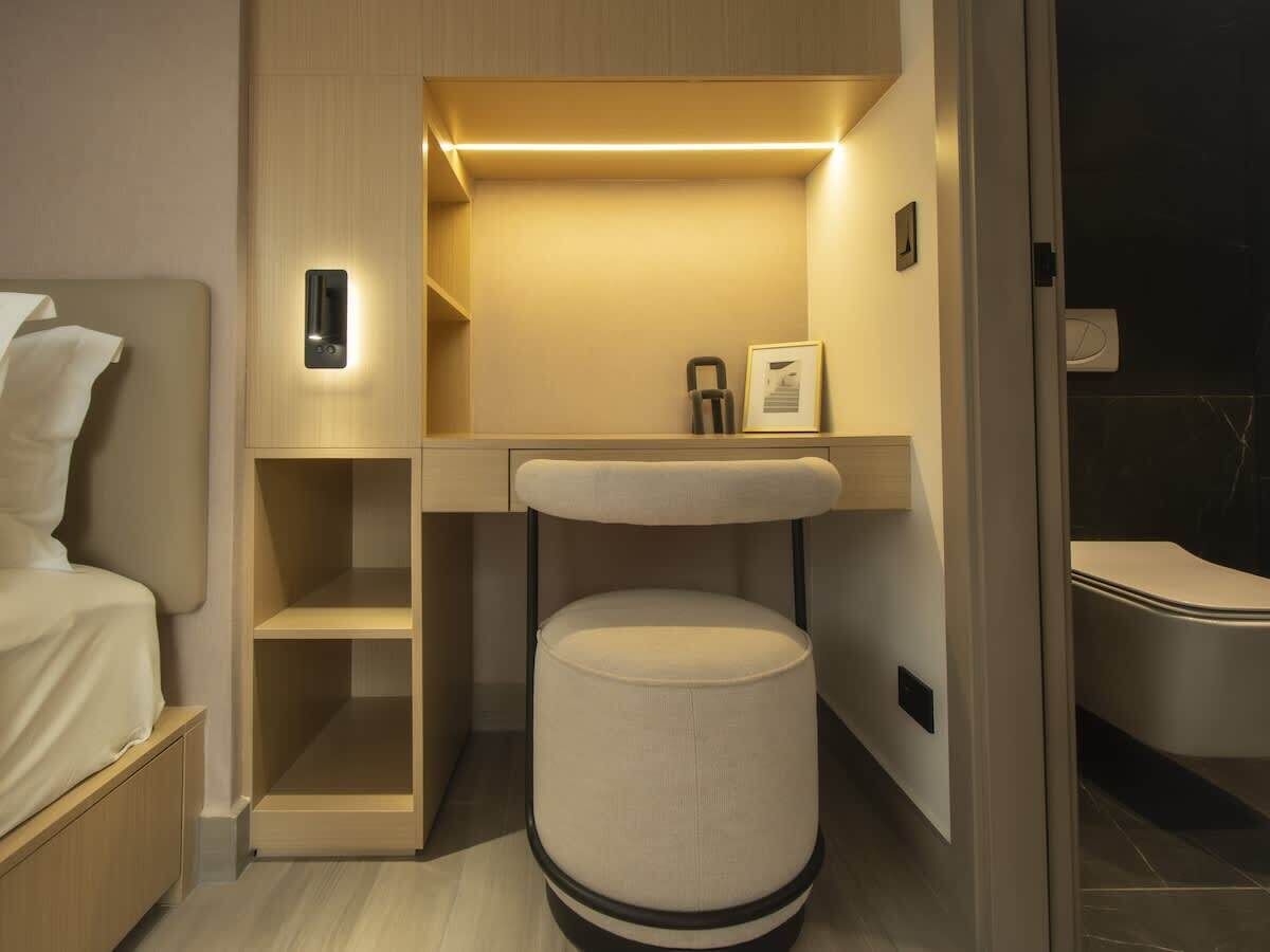 Une chambre d’hôtel de taille réduite, comprenant un lit, un petit bureau, une chaise et des toilettes.