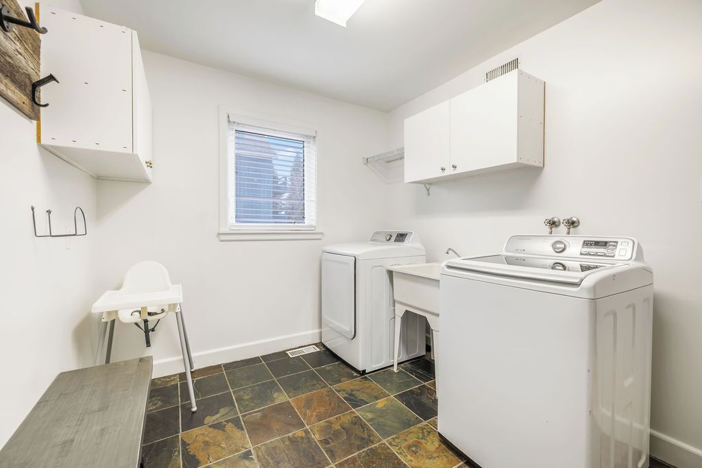 A laundry room with a washing machine, dryer, and a small table.
