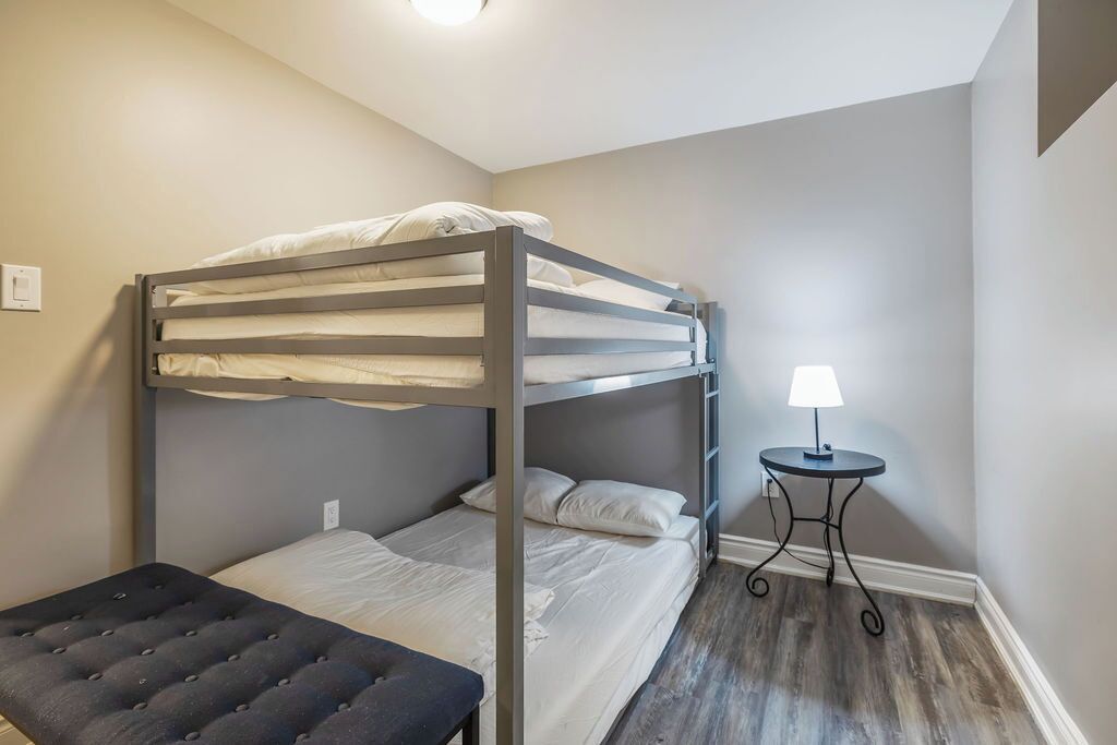 Une chambre avec un lit superposé, une petite table et un banc.