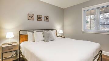 A neatly made bed with white linens and pillows, two bedside tables with lamps, and three wall-mounted animal-themed pictures.