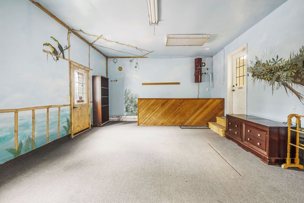 A room with a wooden bench, a wooden cabinet, and a door.