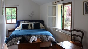 Une chambre à coucher avec un lit, une chaise, une table, un radiateur et une fenêtre.