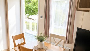 Un espacio habitable compacto con una mesa de comedor, dos sillas, un televisor y una ventana con cortinas.