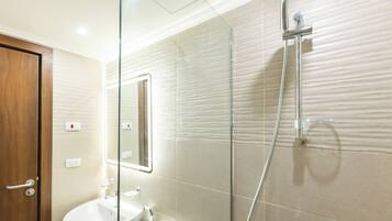 A bathroom with a glass shower enclosure, a sink, and a mirror.