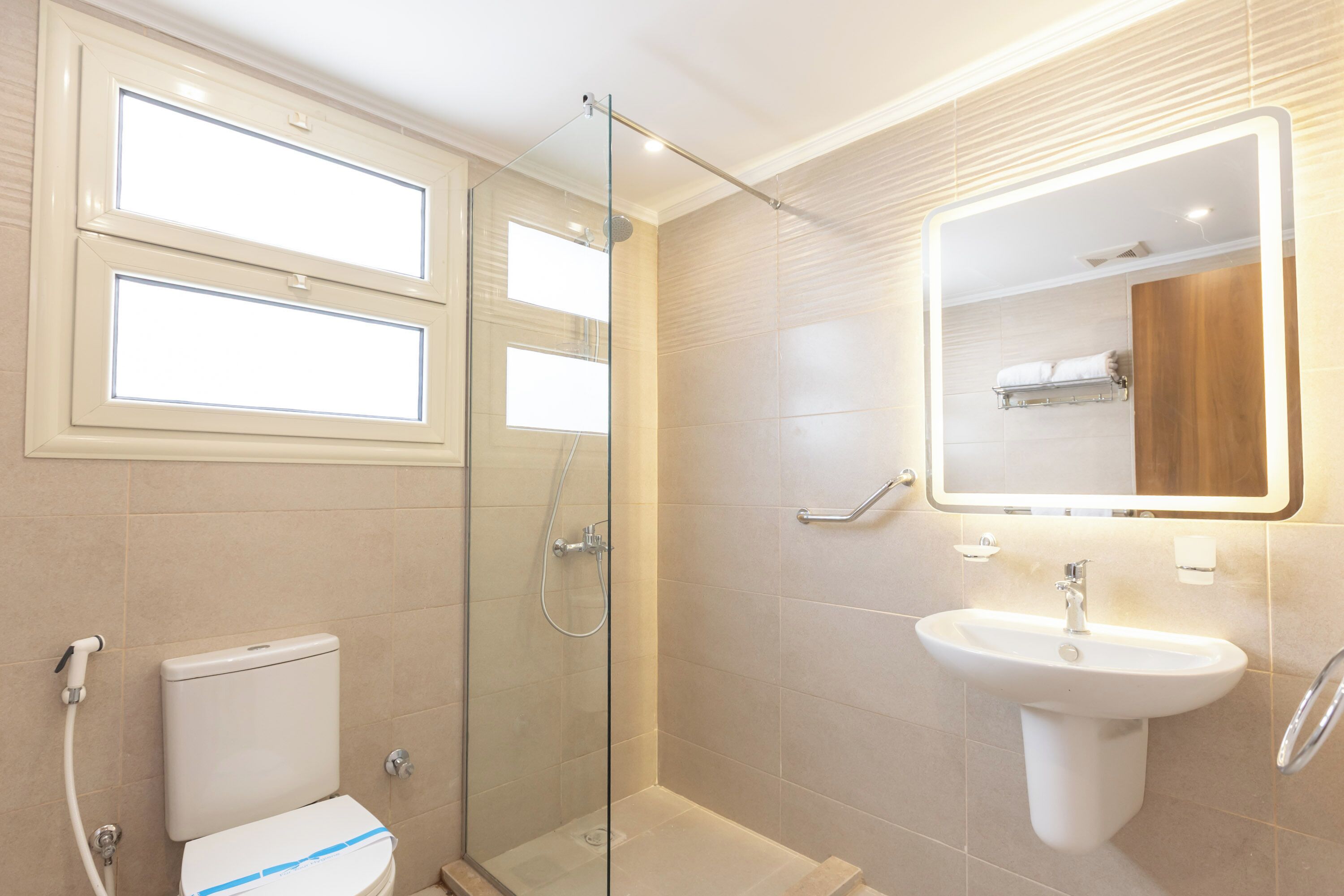 A modern bathroom with a glass-enclosed shower, a white sink, and a mirror above it.