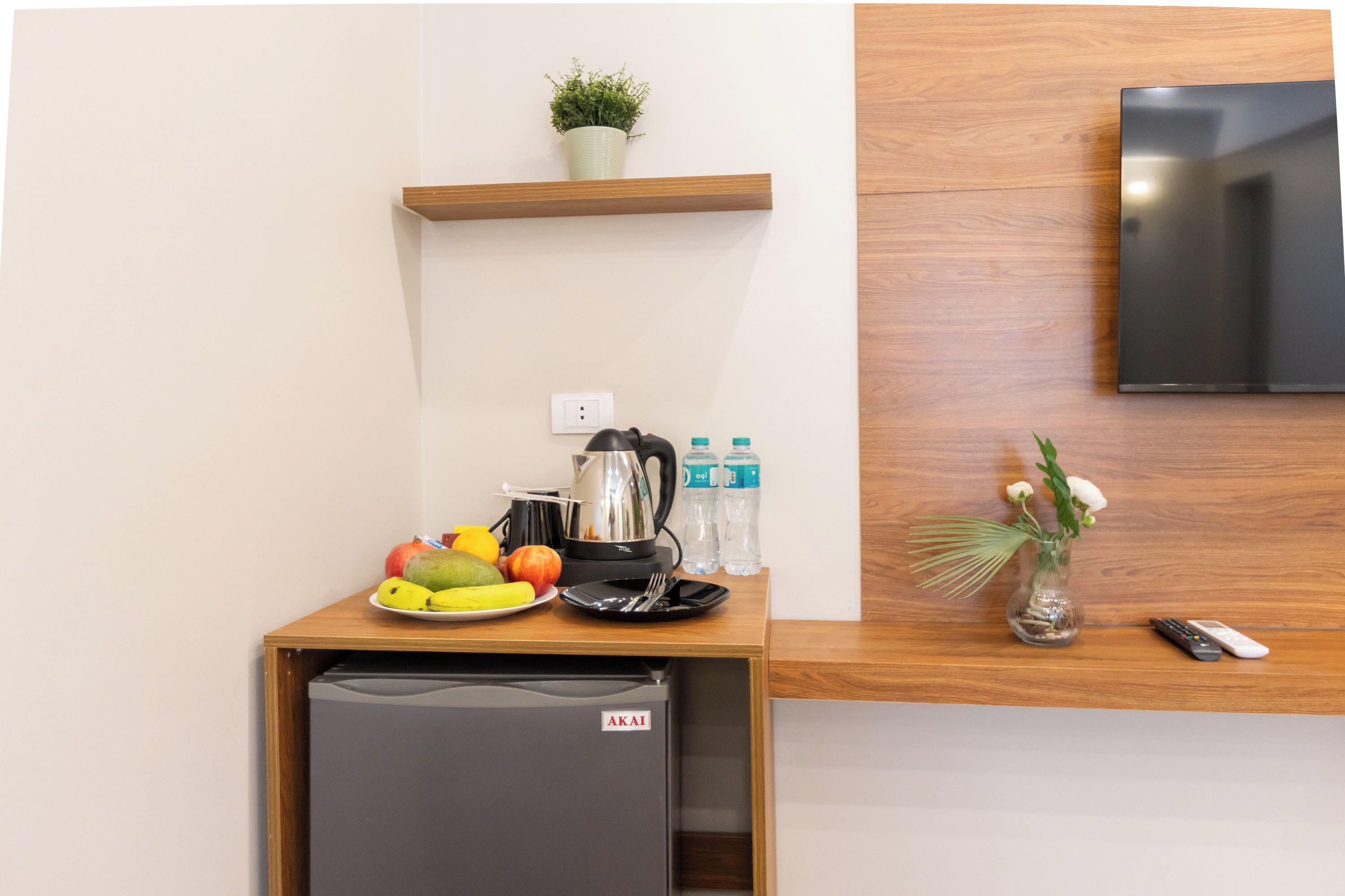 Una kitchenette compacta con un refrigerador pequeño, una cafetera y una bandeja de fruta.