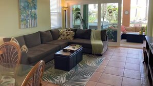 A living room with a sofa, coffee table, and chairs. There is a painting on the wall and a ceiling fan. - Beachfront Paradise! Dog friendly 3 bedroom condo! (Flagler Beach)