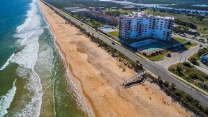 A coastal hotel with a beachfront view, a swimming pool, and a road running parallel to the beach. - Beachfront Paradise! Dog friendly 3 bedroom condo! (Flagler Beach)