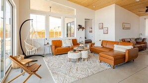 Ein geräumiges Wohnzimmer mit Ledersofas, einem Hängesessel und einem großen Fenster.