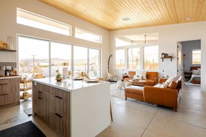 Un vaste espace de vie comprenant un grand îlot central, un canapé et une table à manger.
