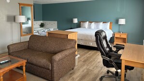 A hotel room with a bed, a desk, a chair, a sofa, and a bathroom with a bathtub. - Simply Home Inn & Suites (Robinson)
