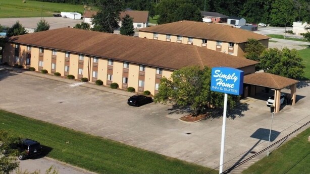 A motel with a parking lot, a covered parking area, and a sign for 'Simply Home Inn & Suites.'