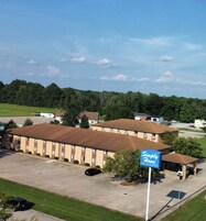Un motel con estacionamiento, una zona de estacionamiento techada y un cartel que dice 'Simply Home Inn & Suites'.