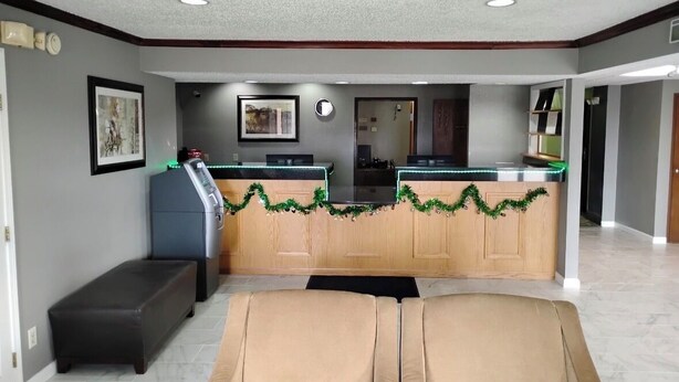 A hotel lobby with a reception desk, a bench, and a sofa. - Simply Home Inn & Suites (Robinson)