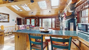 Een rustiek houten interieur met een eethoek, een grote houten tafel en een stenen openhaard.