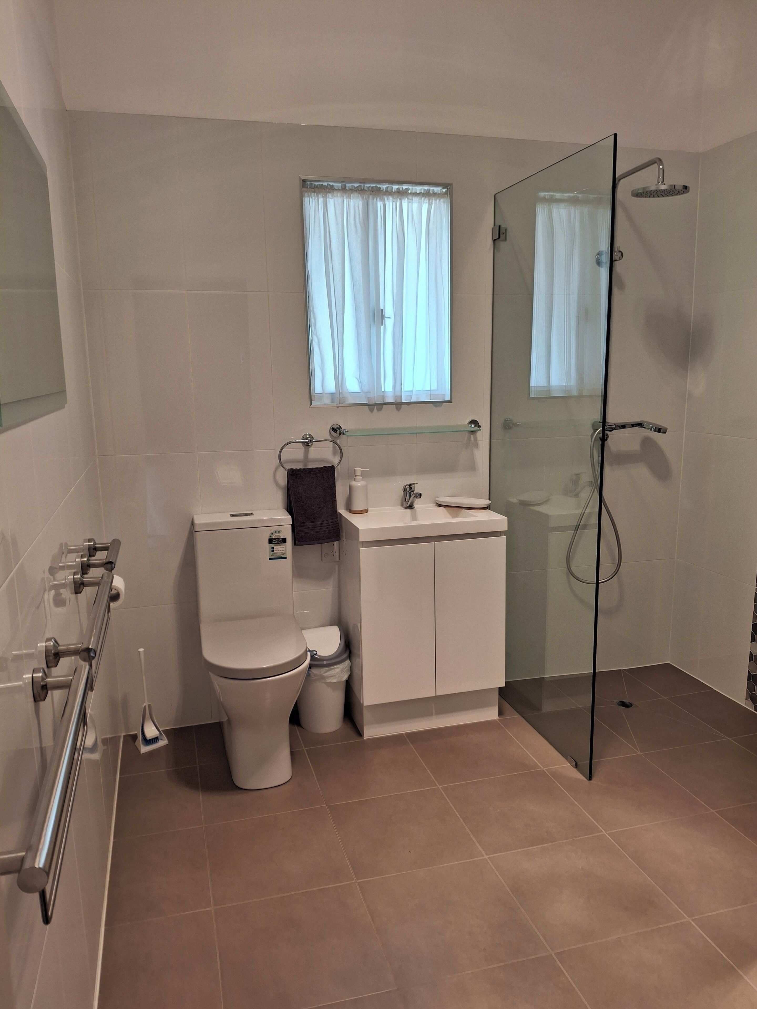 Une salle de bain moderne équipée de toilettes, d’un lavabo et d’une douche à parois de verre.