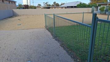 Un espace extérieur clos, avec un chemin de gravier et une zone herbeuse.