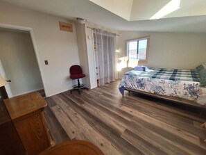 A bedroom with a bed, a chair, a wooden cabinet, and a door leading to another room. - Spacious 3-bedroom Harrison house with AC and scenic Hottub (Harrison)
