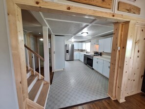 A spacious kitchen with white cabinets, a stainless steel refrigerator, and a built-in oven. - Spacious 3-bedroom Harrison house with AC and scenic Hottub (Harrison)