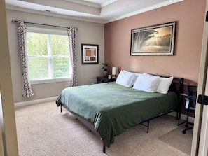 A bedroom with a bed, a window with curtains, a nightstand, a lamp, and a framed picture on the wall. - 3BR Sleeps 10 w/King Beds, Artful Design & Central (Raleigh)