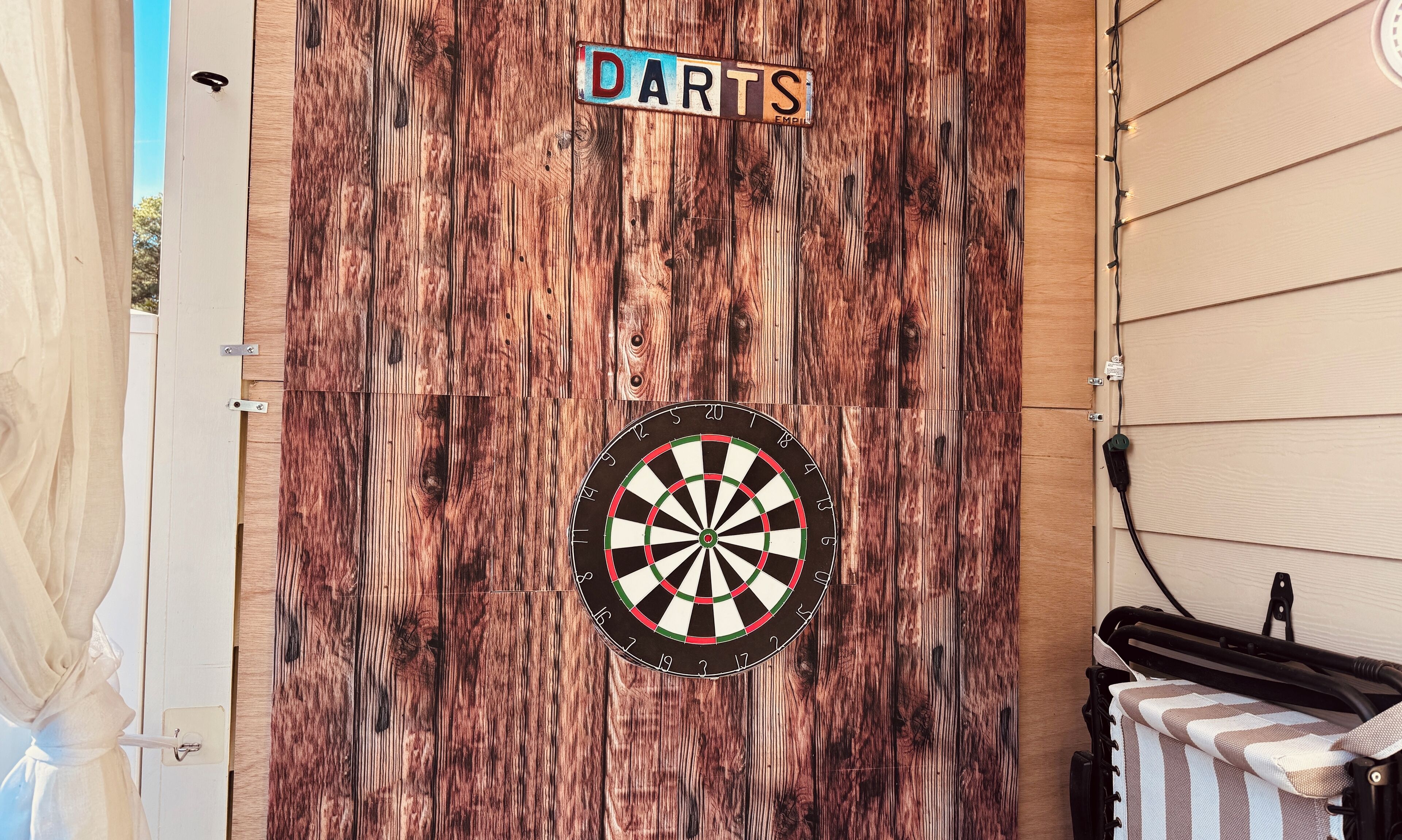 A dartboard mounted on a wooden wall with a sign above it that reads "DARTS".