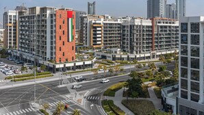 A modern urban area with high-rise buildings, a well-maintained road, and greenery. - Stayshort - Studio Apartment at Azizi Riviera With Balcony (Dubai)