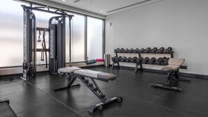 A gym with weightlifting equipment, benches, and dumbbells. - Stayshort - Studio Apartment at Azizi Riviera With Balcony (Dubai)