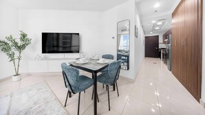 A modern dining area with a flat-screen TV, a dining table set for four, and a potted plant. - Stayshort - Studio Sleeps 2 in Business Bay With Canal Views (Dubai)