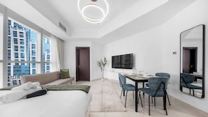 A modern hotel room with a large bed, a dining area with chairs, a TV, and a large window with a city view. - Stayshort - Studio Sleeps 2 in Business Bay With Canal Views (Dubai)