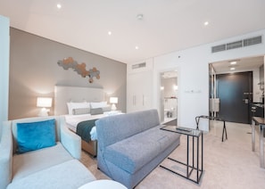 A modern hotel room with a bed, two sofas, a small table, and a kitchenette. - Stayshort - Chic Studio for 3 People in Business Bay (Dubai)