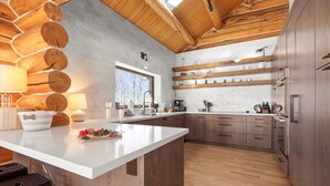 A modern kitchen with a central island, wooden logs on the ceiling, and a large window. - Telluride Escape | Private Decks w/ Views (Telluride)