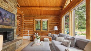 A log cabin interior with a stone fireplace, a sofa, a coffee table, and a painting on the wall. - Telluride Escape | Private Decks w/ Views (Telluride)