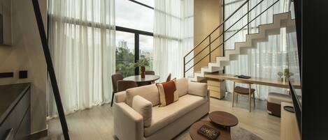 A modern living room with a sofa, coffee table, and a staircase leading to an upper floor.