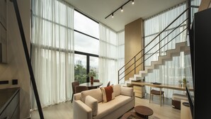 Uma sala de estar moderna com um sofá, mesa de centro e escada que leva a um andar superior.